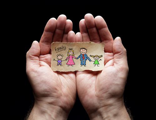 stock photo of hands open and holding a small drawing of a family